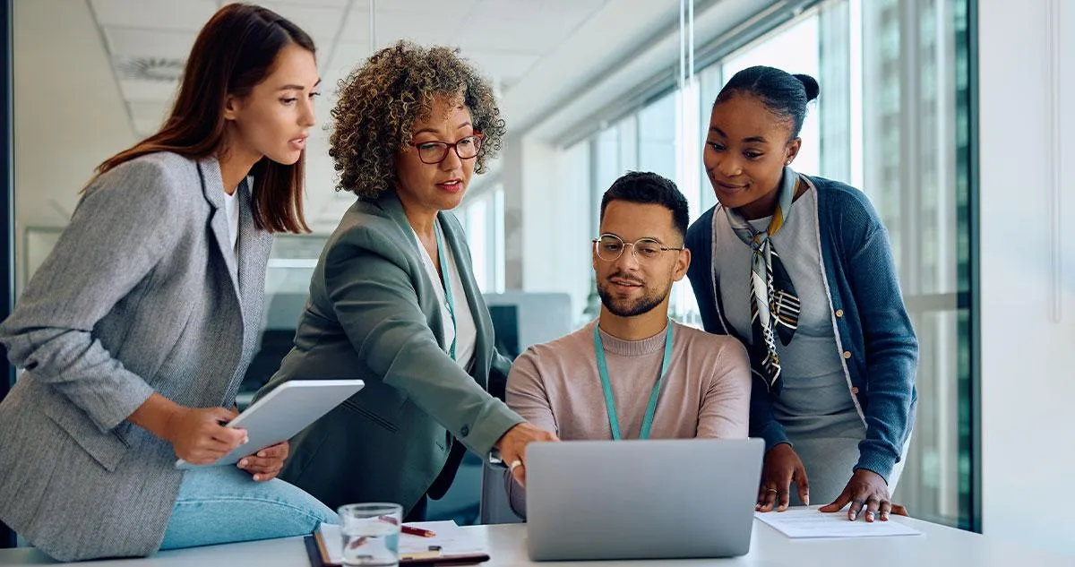 An agency team of four gathered around a laptop, planning work for a client.